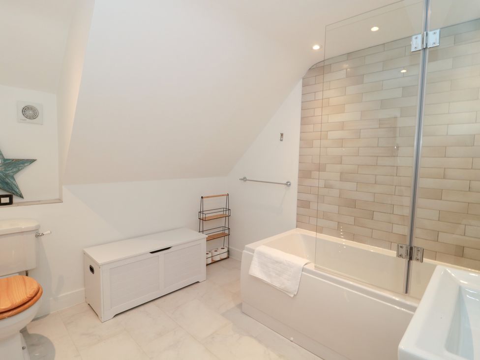 A bathroom with a bathtub and a toilet at Wellinghill Cottage at Wellinghill House Charlton Kings