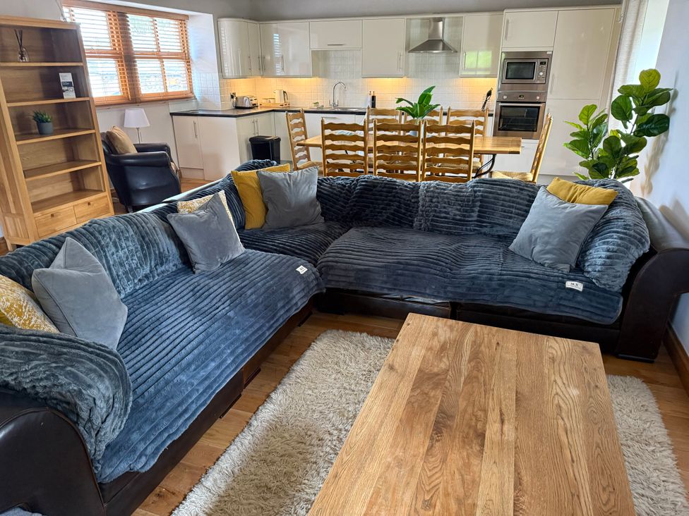 A living room with a sofa, coffee table, and dining area at Old Corner Barn in Troutbeck