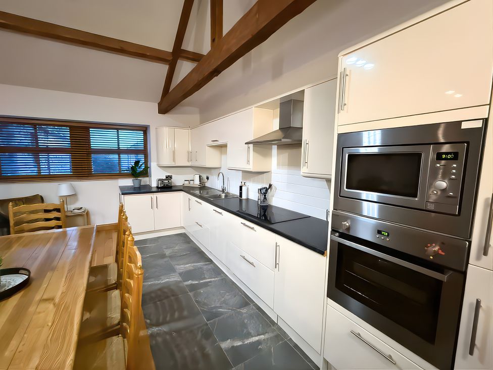 A kitchen with a dining table and appliances at Old Corner Barn in Troutbeck