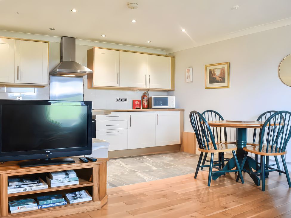 A kitchen with a dining table and television at Crag Barn Cottage in Troutbeck