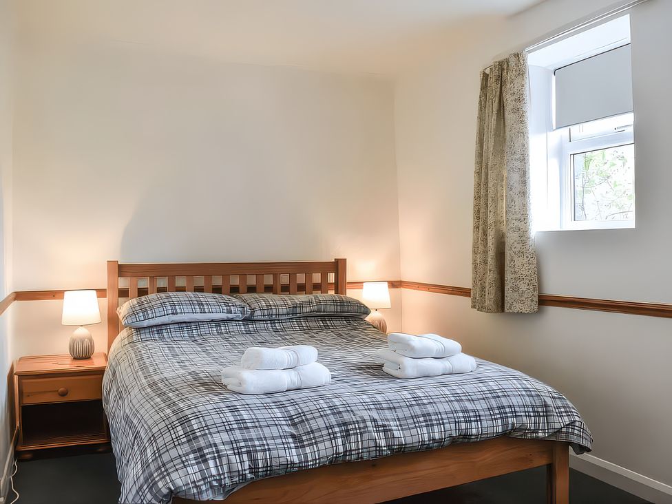 A bedroom with a bed and bedside table at Crag Barn Cottage in Troutbeck