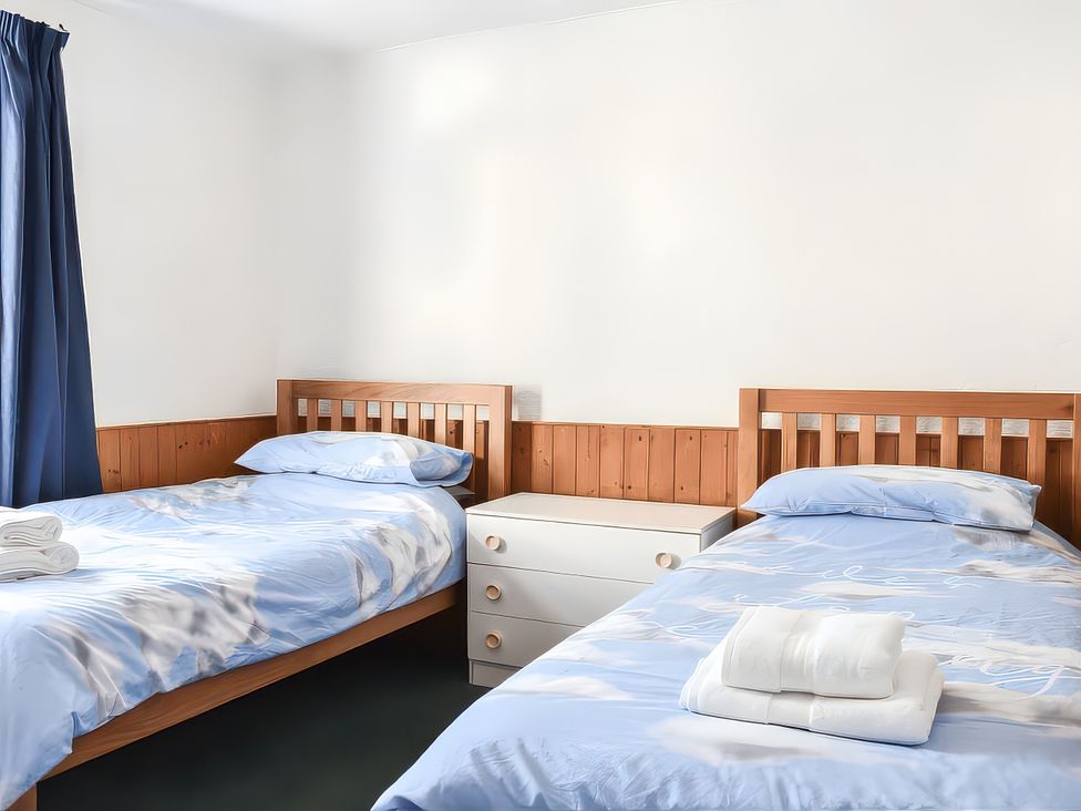 A bedroom with two beds and a dresser at Crag Barn Cottage in Troutbeck
