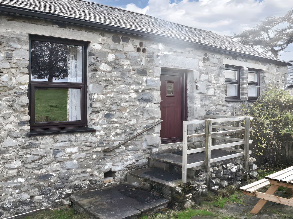 A stone cottage exterior with a wooden door and windows at Crag Barn Cottage in Troutbeck