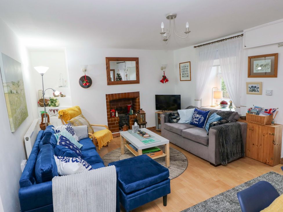 A living room with a sofa, coffee table, and television at Tawe Cottage in Swansea