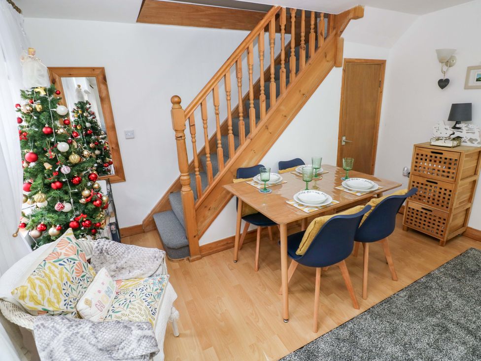A dining room with a table and Christmas tree at Tawe Cottage in Swansea