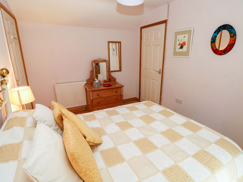 A bedroom with a bed and dresser at Tawe Cottage in Swansea