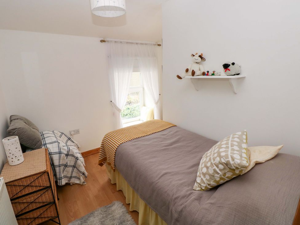 A bedroom with a bed and toys on a shelf at Tawe Cottage Swansea