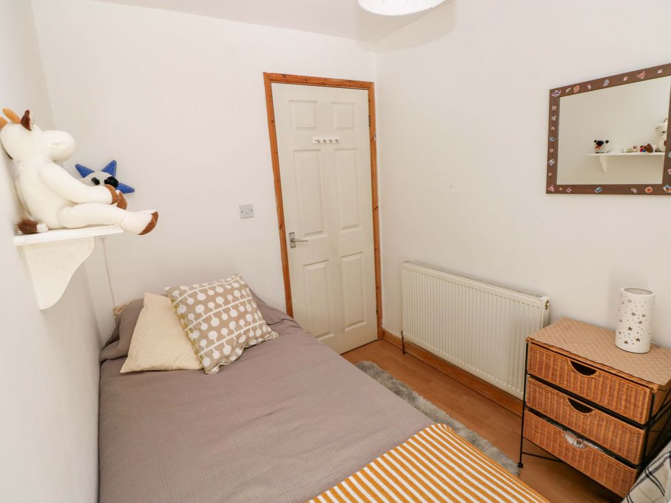 A bedroom with a bed and a mirror at Tawe Cottage Swansea