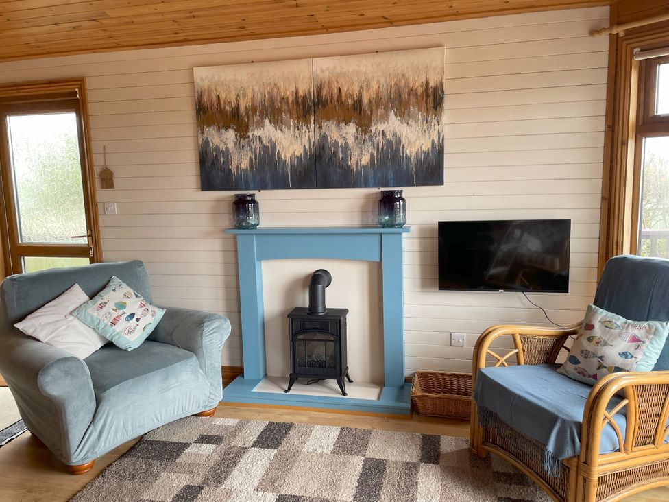 A living room with a fireplace and a television at Lamorna in Sennen