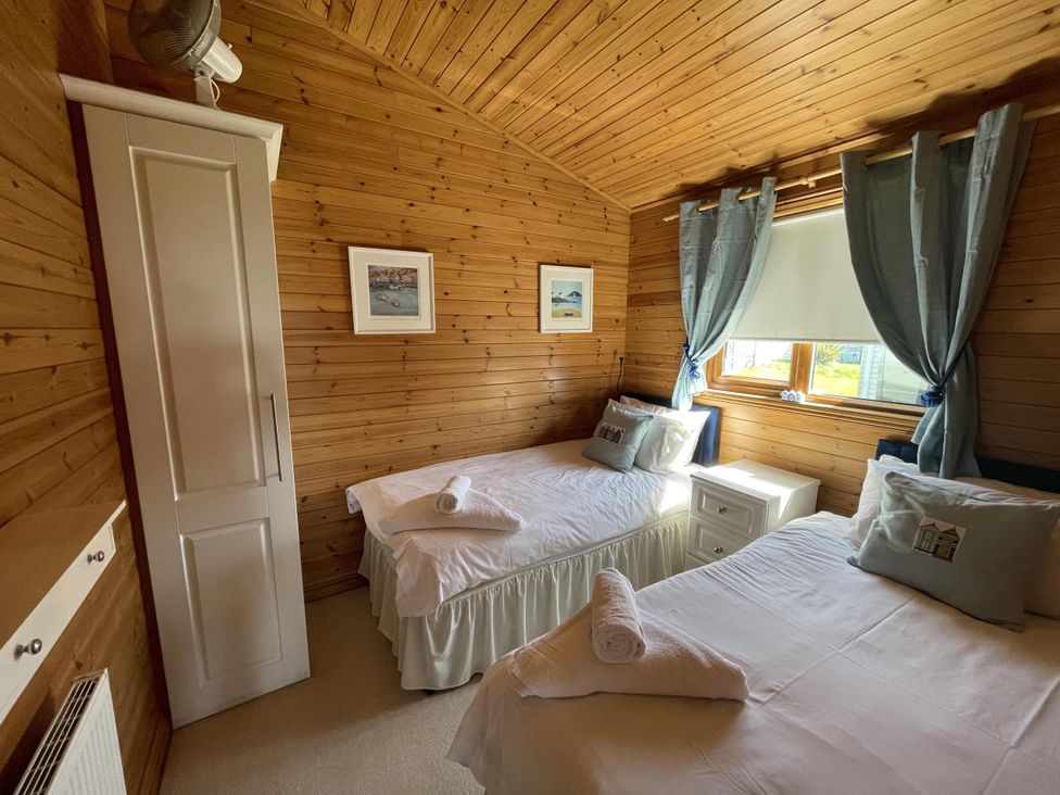 A bedroom with two beds and a wardrobe at Lamorna Sennen