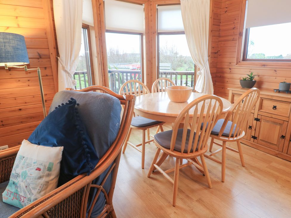 A dining room with a round table and chairs at Lamorna in Sennen