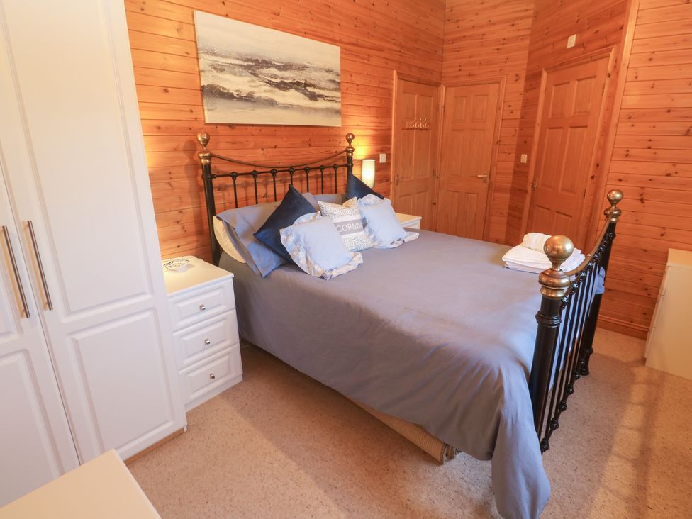 A bedroom featuring a bed with pillows and a wardrobe at Lamorna Sennen