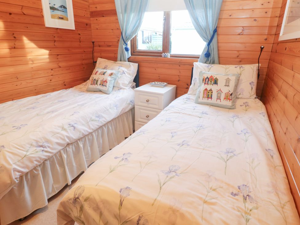 A bedroom with two beds and a bedside table at Lamorna Sennen