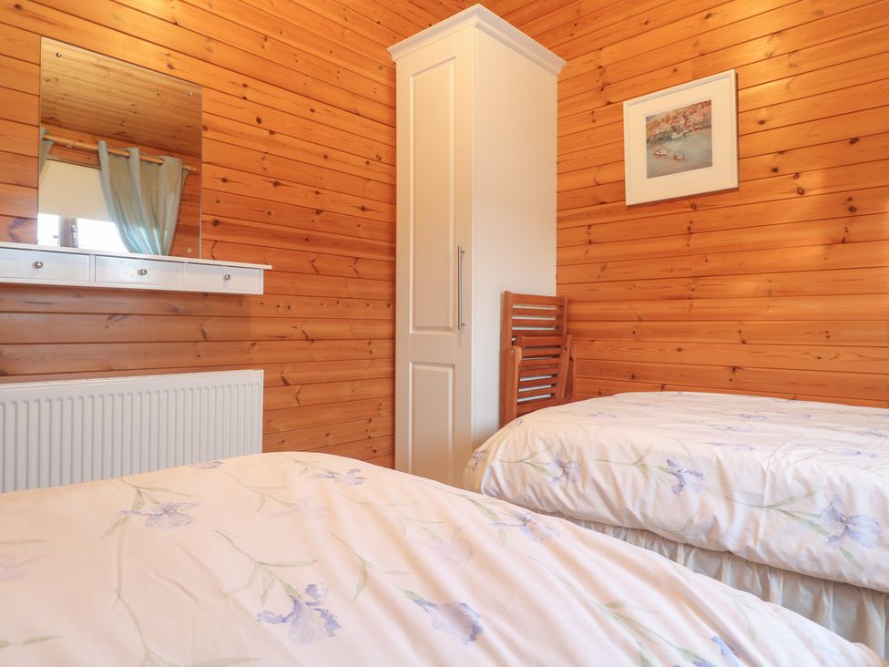 A bedroom with two beds and a wardrobe at Lamorna in Sennen