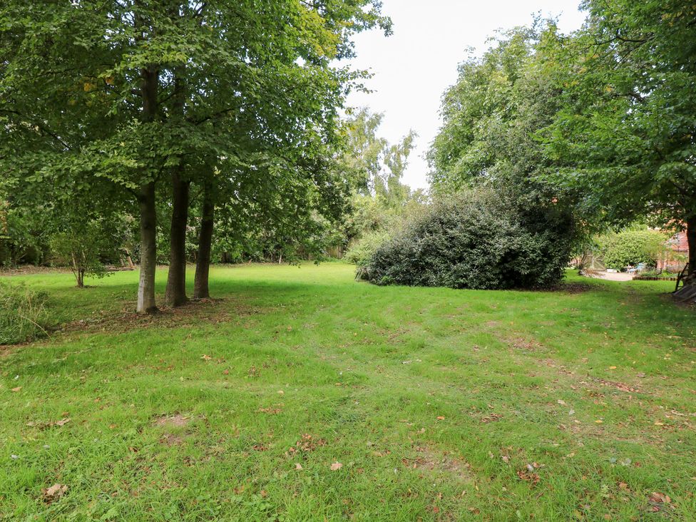 A garden with trees and grass at The Retreat in Norwich