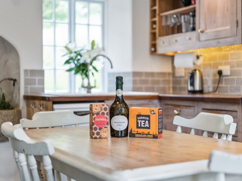 A kitchen with a table displaying a bottle, ginger cookies, and tea at Treovis Cottage in Callington