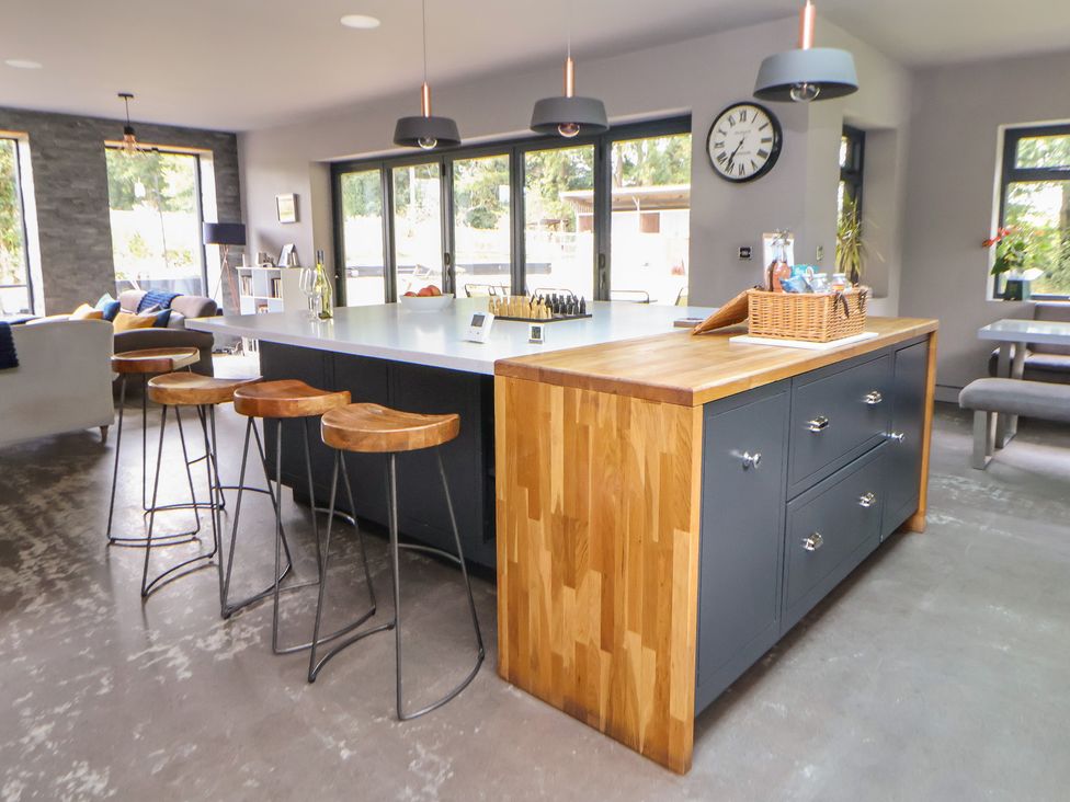 A kitchen with bar stools and a kitchen island at Rook Hall Farm Butterton near Newcastle-Under-Lyme