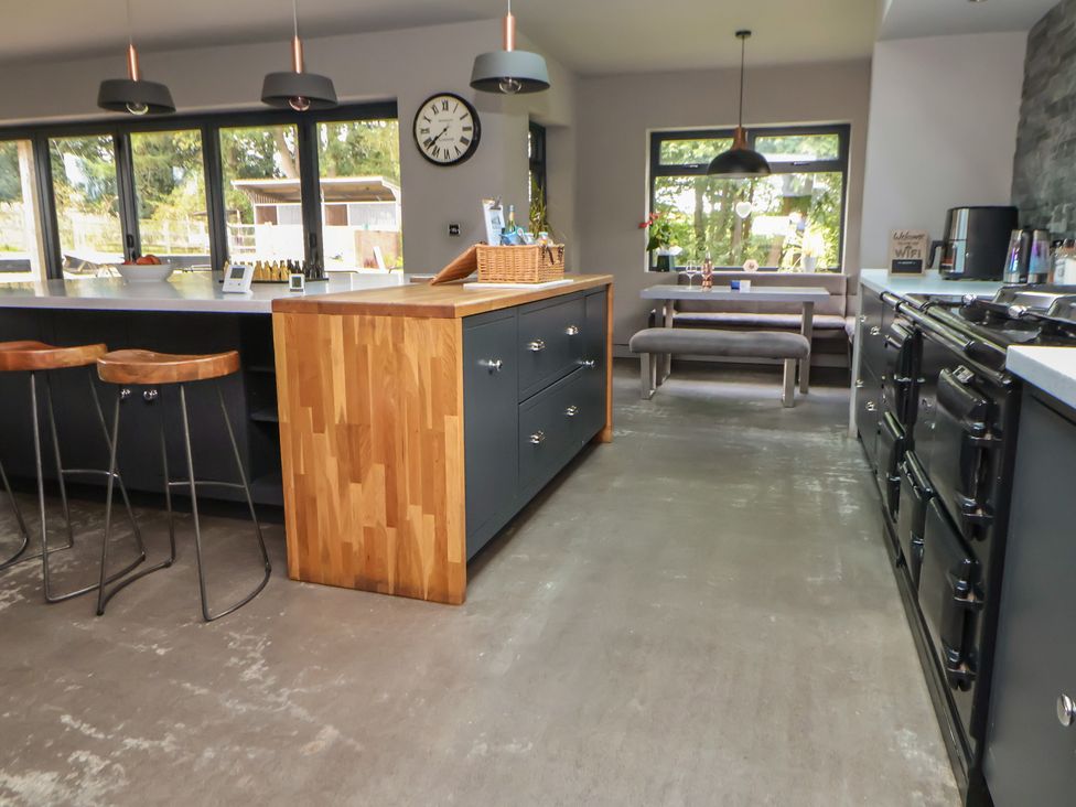A kitchen with island, bar stools, and table seating at Rook Hall Farm in Butterton near Newcastle-Under-Lyme