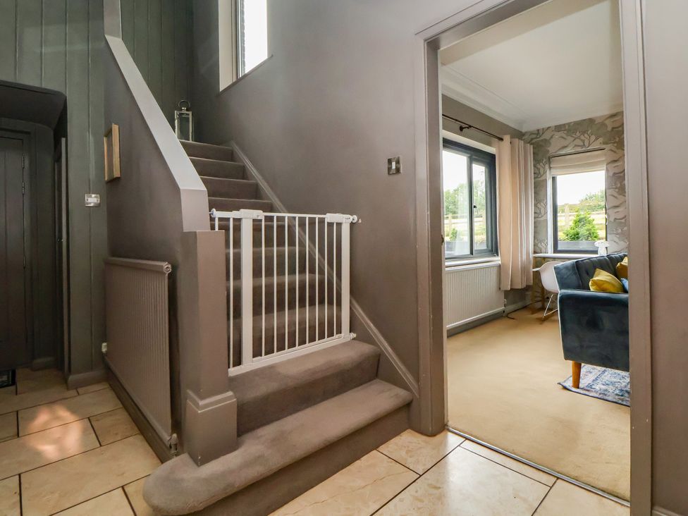 A hallway with a staircase and safety gate at Rook Hall Farm Butterton near Newcastle-Under-Lyme