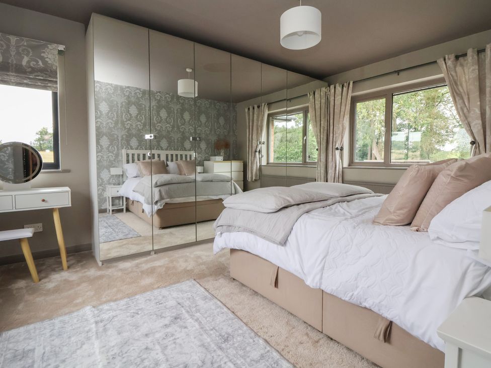 A bedroom with a bed, mirror, and wardrobe at Rook Hall Farm in Butterton near Newcastle-Under-Lyme