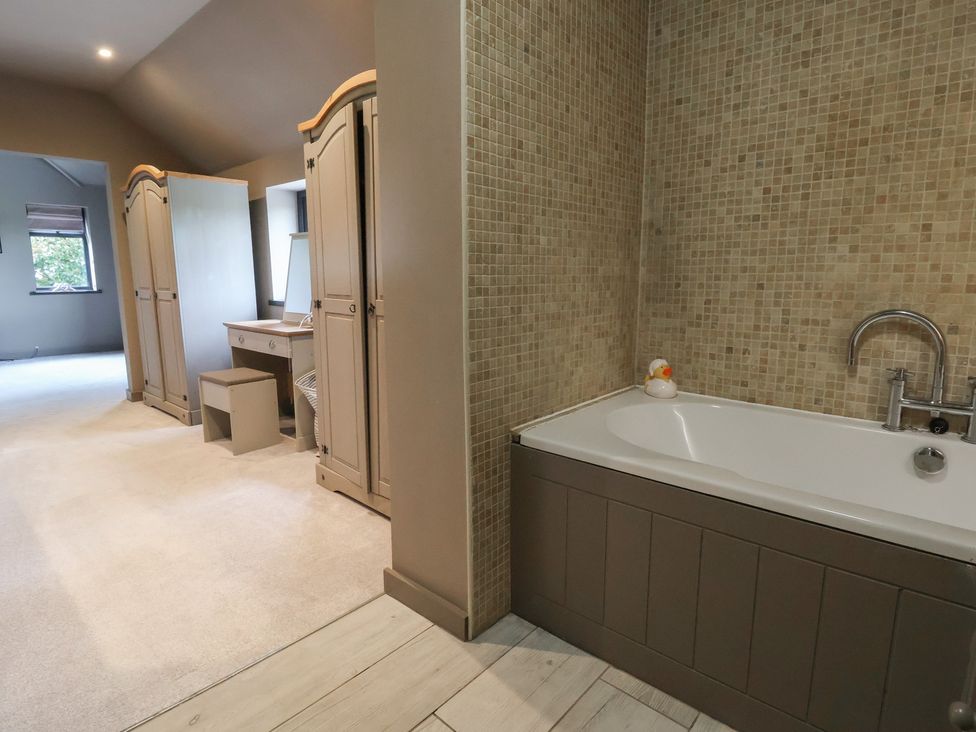 A bathroom with a bathtub and storage cabinets at Rook Hall Farm Butterton near Newcastle-Under-Lyme