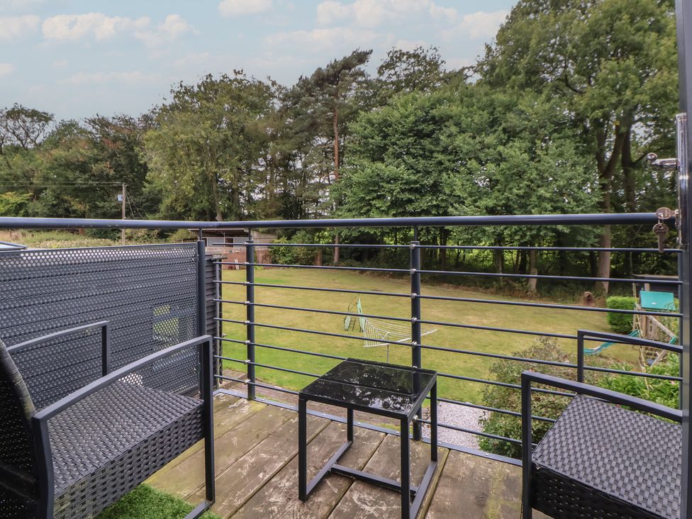 A balcony with chairs and table overlooking a garden at Rook Hall Farm Butterton near Newcastle-Under-Lyme