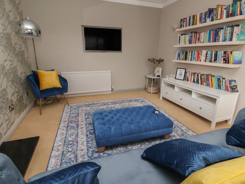 A living room with a sofa, ottoman, and bookshelves at Rook Hall Farm in Butterton near Newcastle-Under-Lyme