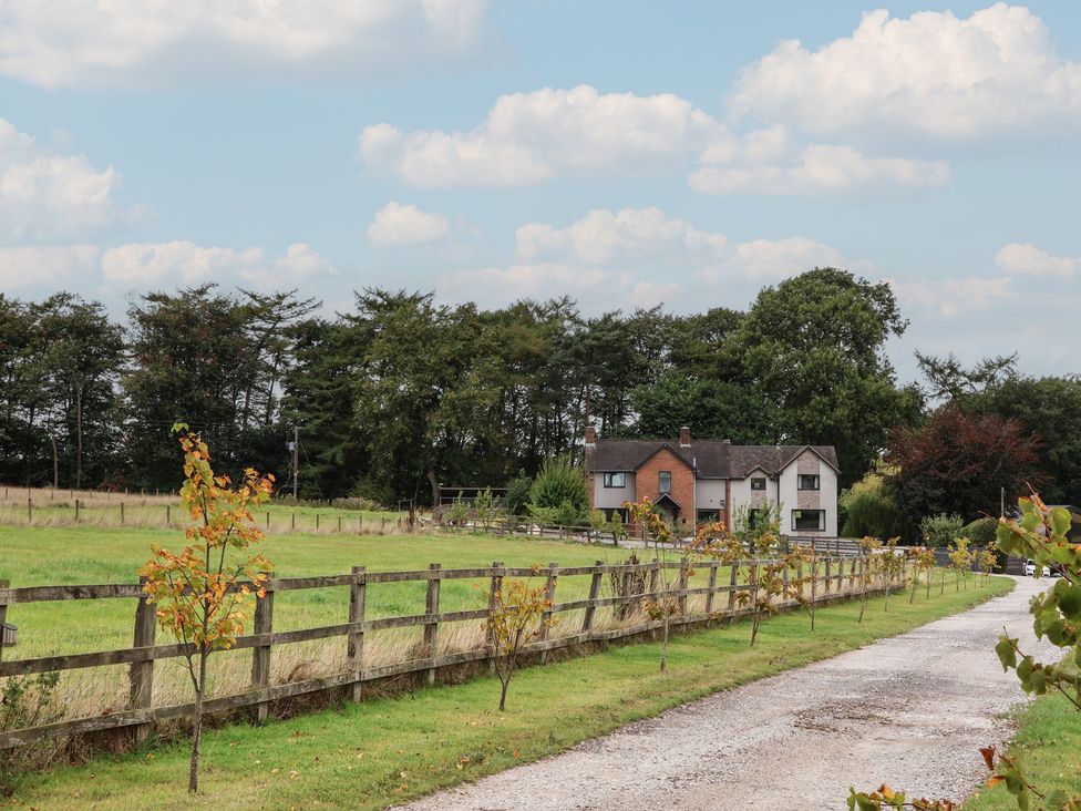 A house surrounded by trees and a fence with a gravel driveway at Rook Hall Farm Butterton near Newcastle-Under-Lyme