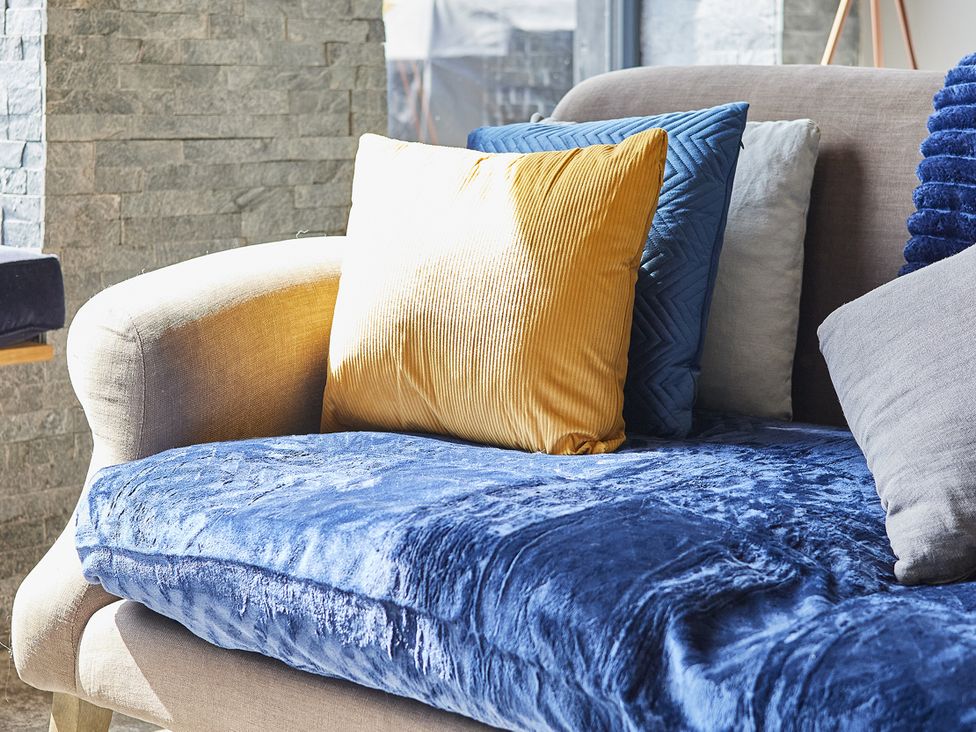 A sofa with cushions and a throw blanket at Rook Hall Farm in Butterton near Newcastle-Under-Lyme