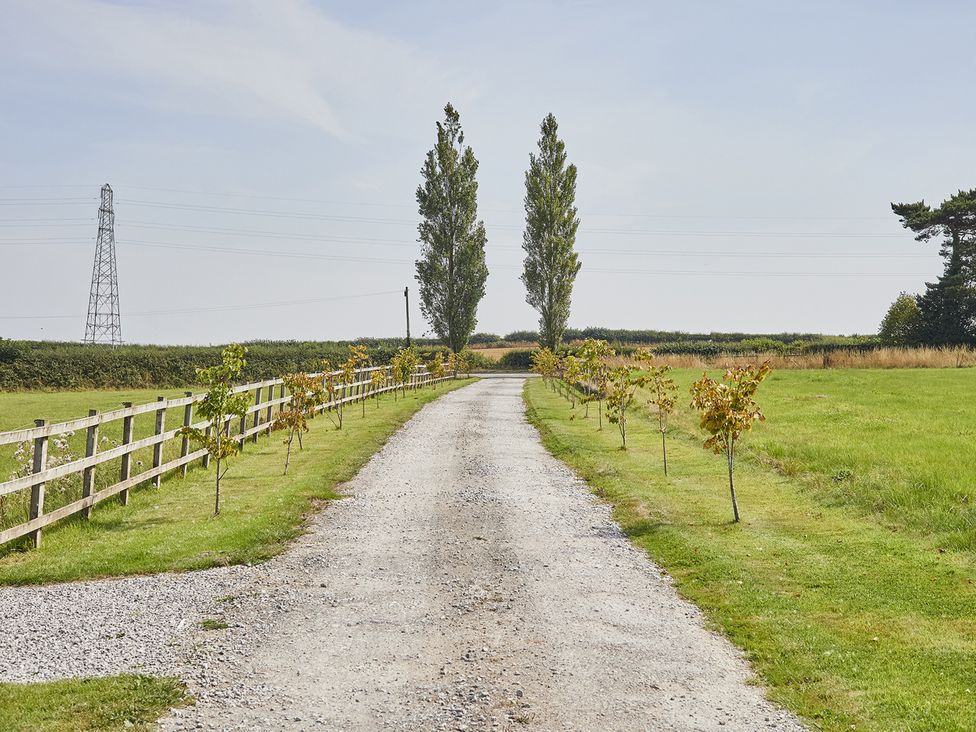 A gravel road lined with trees and a fence at Rook Hall Farm Butterton near Newcastle-Under-Lyme