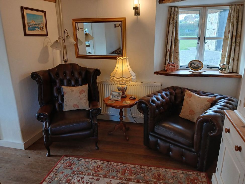 A living room with armchairs and a table at Sheepwash Barn