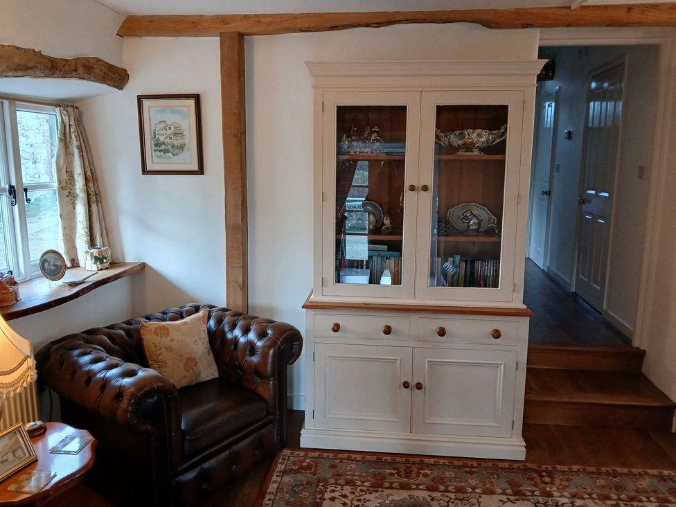 A living room with a chair and a display cabinet at Sheepwash Barn in 