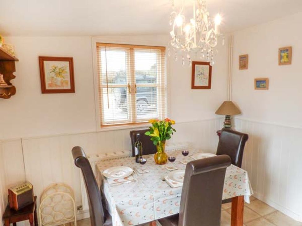 A dining room with a table set for dinner with flowers at Sheepwash Barn in 