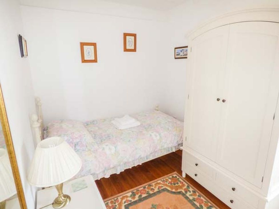 A bedroom with a bed, wardrobe and lamp at Sheepwash Barn