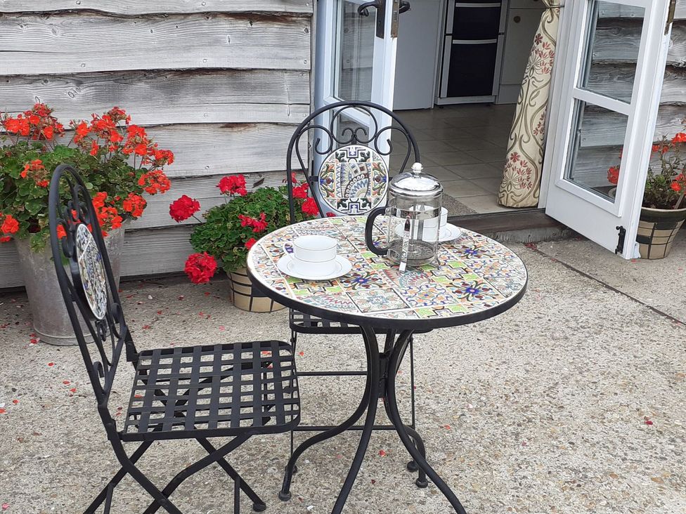 A table and chairs with a tea set and flowers at Sheepwash Barn