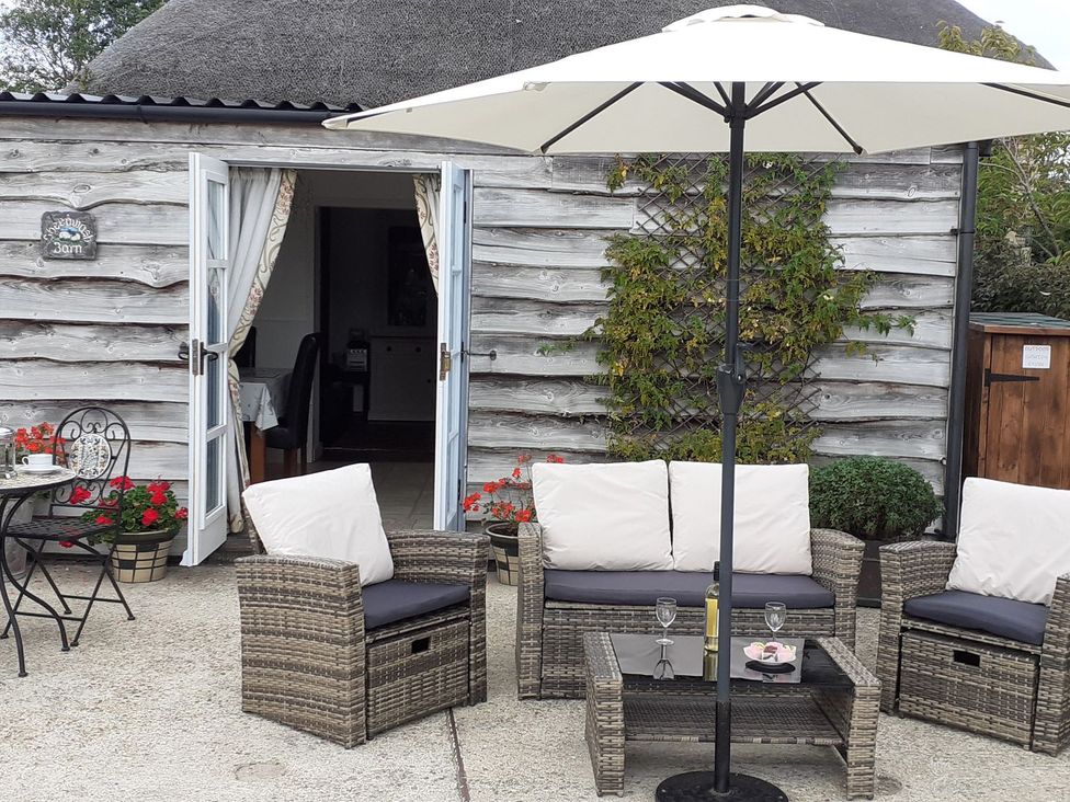 An outdoor seating area with chairs and a table at Sheepwash Barn