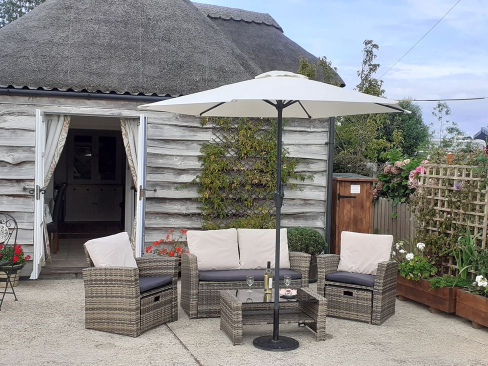An outdoor patio with seating and an umbrella at Sheepwash Barn
