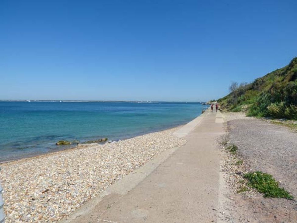 A beach with a pathway and water at Sheepwash Barn