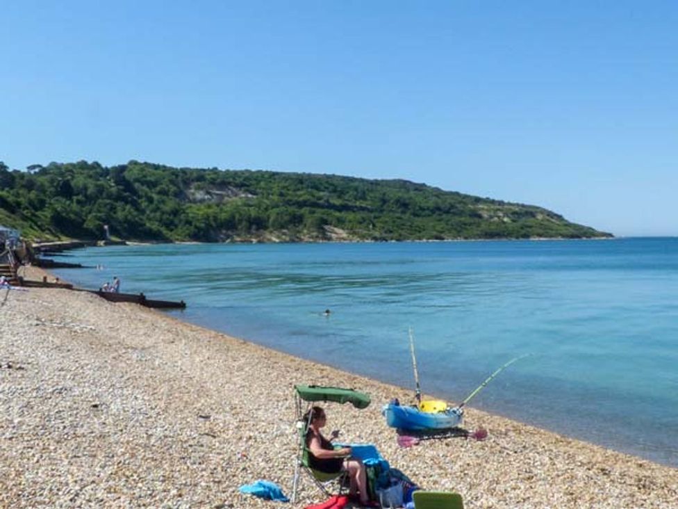 A beach with people and a boat at Sheepwash Barn in 