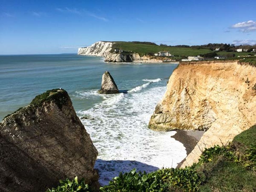 A coastal landscape with cliffs and a rock formation by the sea at Sheepwash Barn 