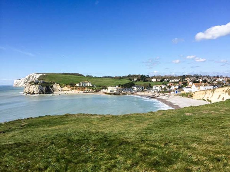 A coastal view with cliffs and houses near water at Sheepwash Barn