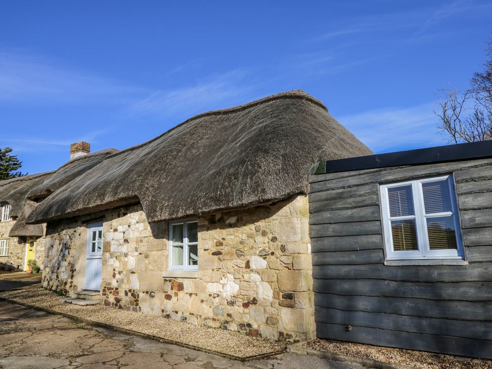 A house with thatched roof and stone wall at Sheepwash Barn in Freshwater