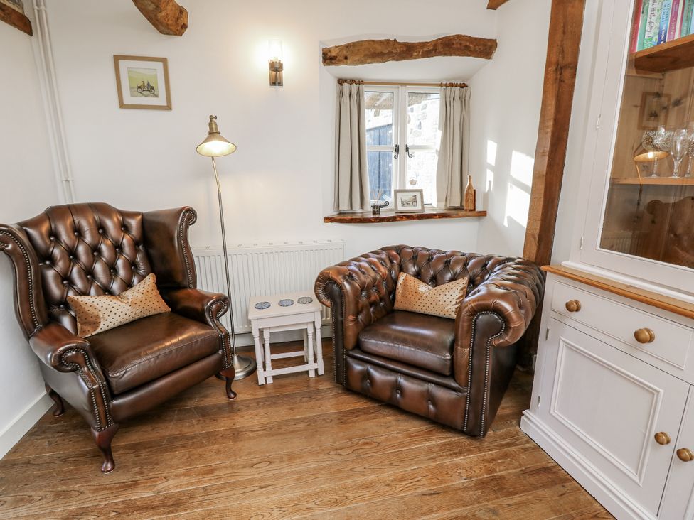 A sitting room with two brown armchairs and a table at Sheepwash Barn in Freshwater