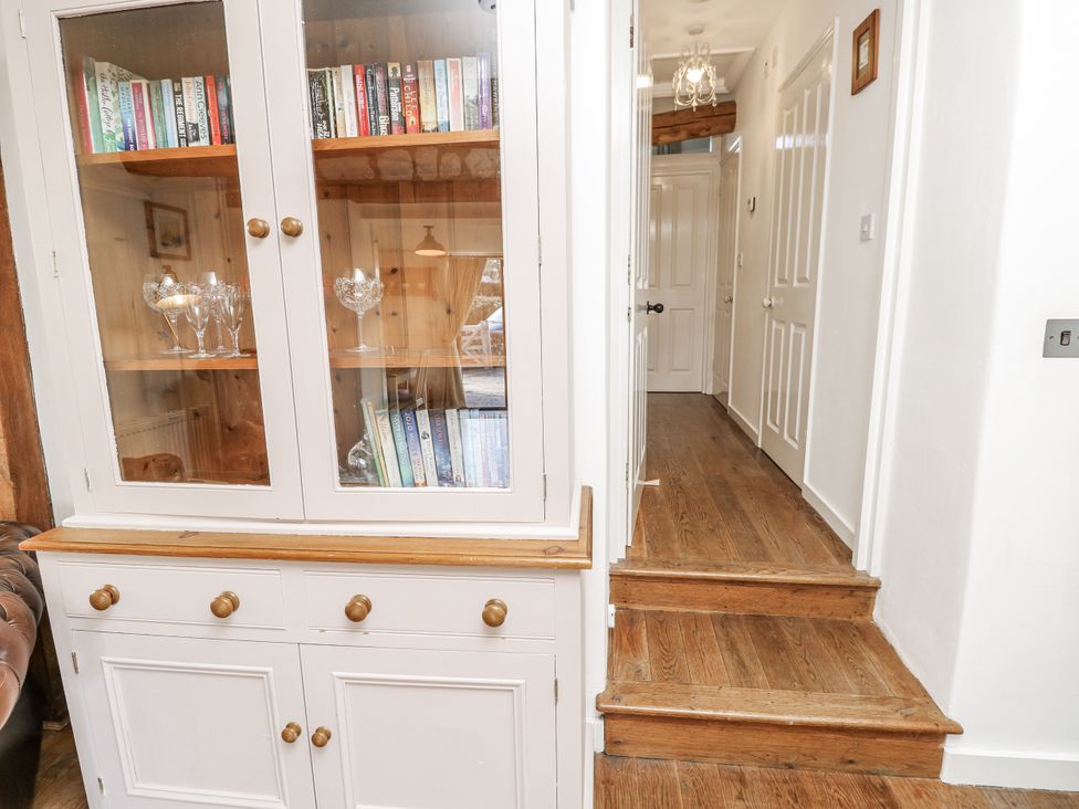 A hallway with a cabinet and staircase at Sheepwash Barn in Freshwater