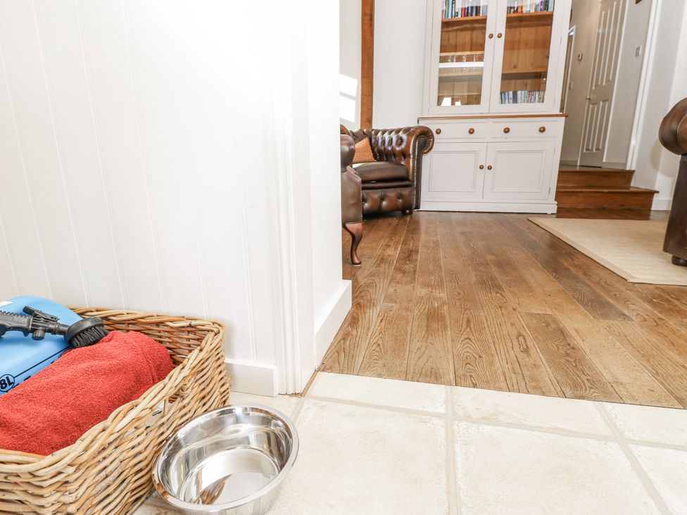 A living room with a basket and dog bowl at Sheepwash Barn in Freshwater