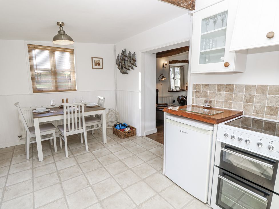 A kitchen with a dining table and appliances at Sheepwash Barn in Freshwater