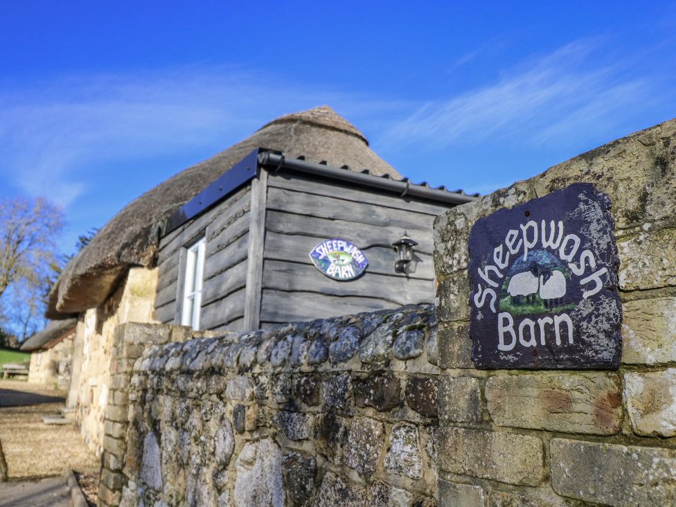 A building with a thatched roof and a sign at Sheepwash Barn Freshwater