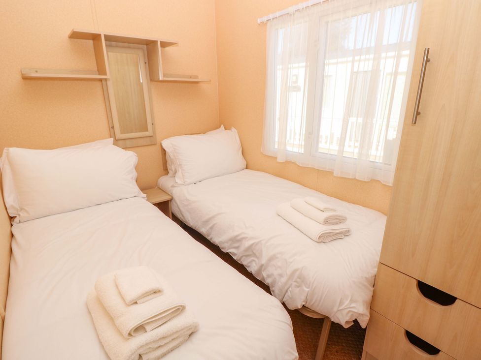 A bedroom with two beds and a mirrored shelf at Number 38 Chichester