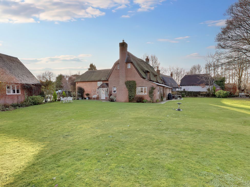A house with a large garden and outdoor furniture at Lake Cottage in Swindon