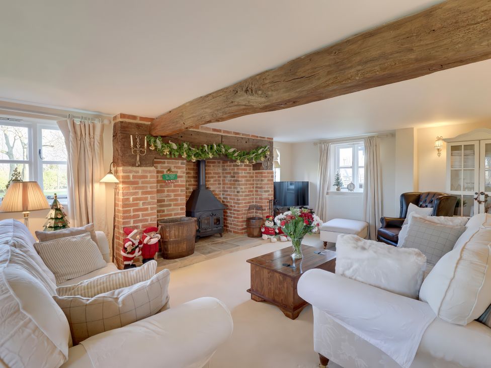 A living room with a fireplace and furniture at Lake Cottage in Swindon